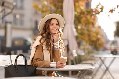 Photo of Stylish woman at table in outdoor cafe. Autumn mood