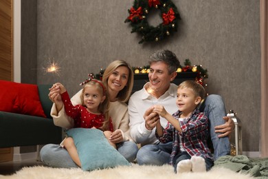 Photo of Lovely family with Christmas sparklers at home