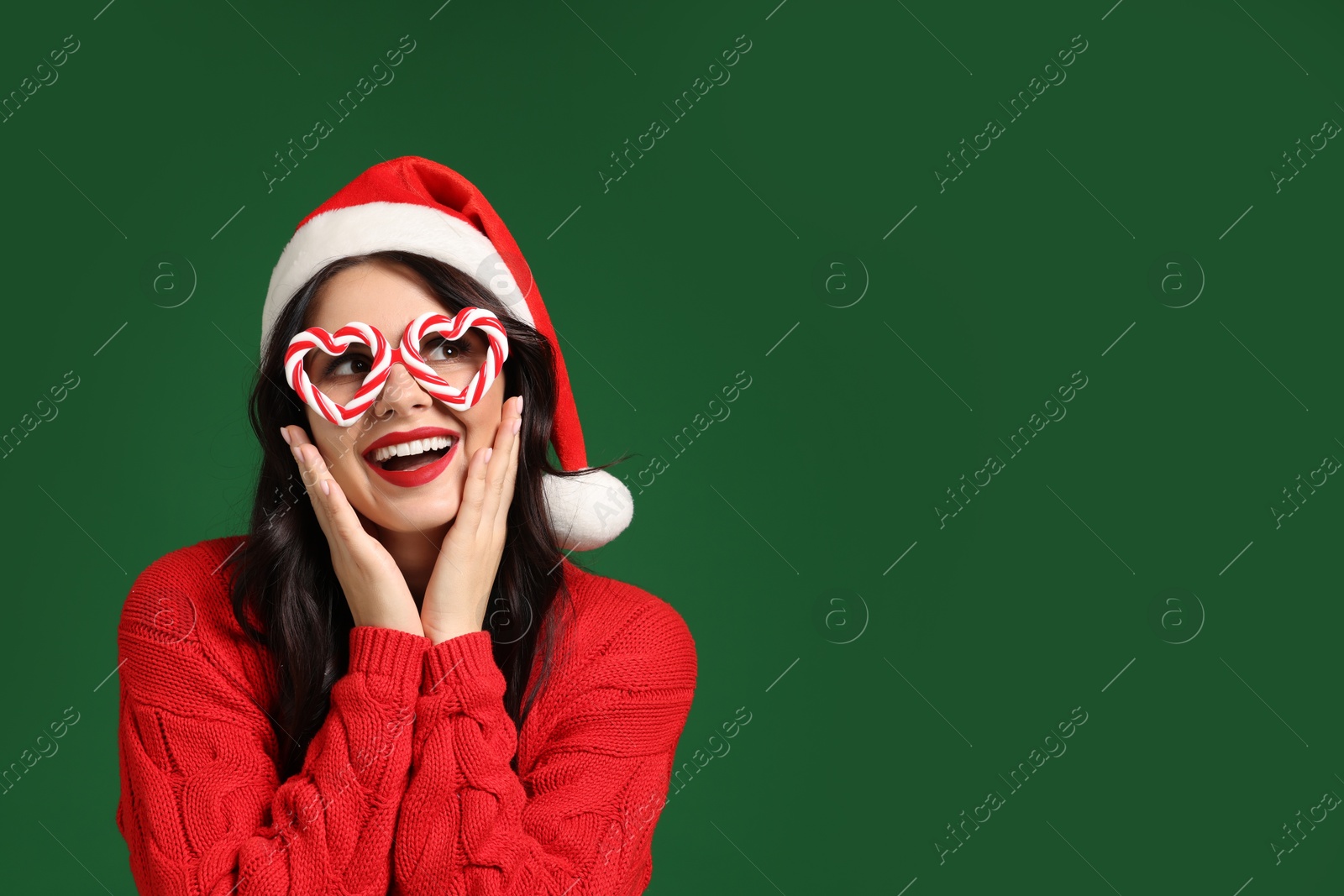 Photo of Beautiful woman in Santa hat and party glasses on green background, space for text. Christmas celebration