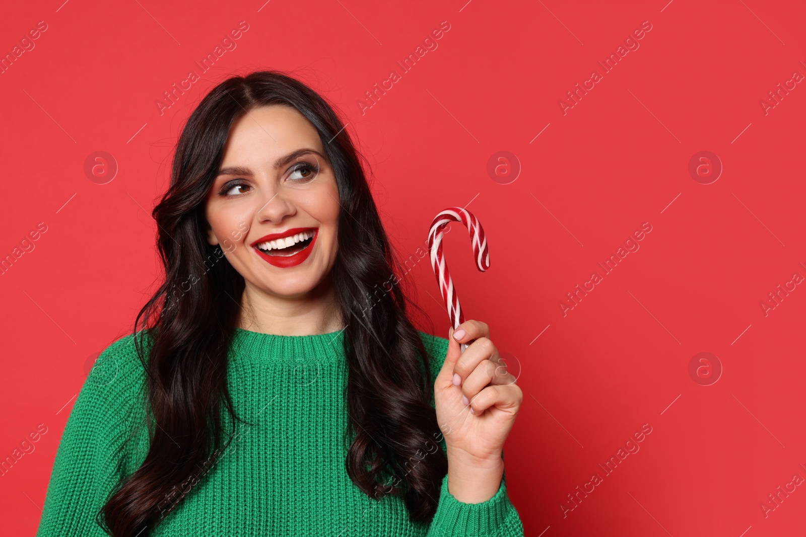 Photo of Beautiful woman with candy cane on red background, space for text. Christmas celebration