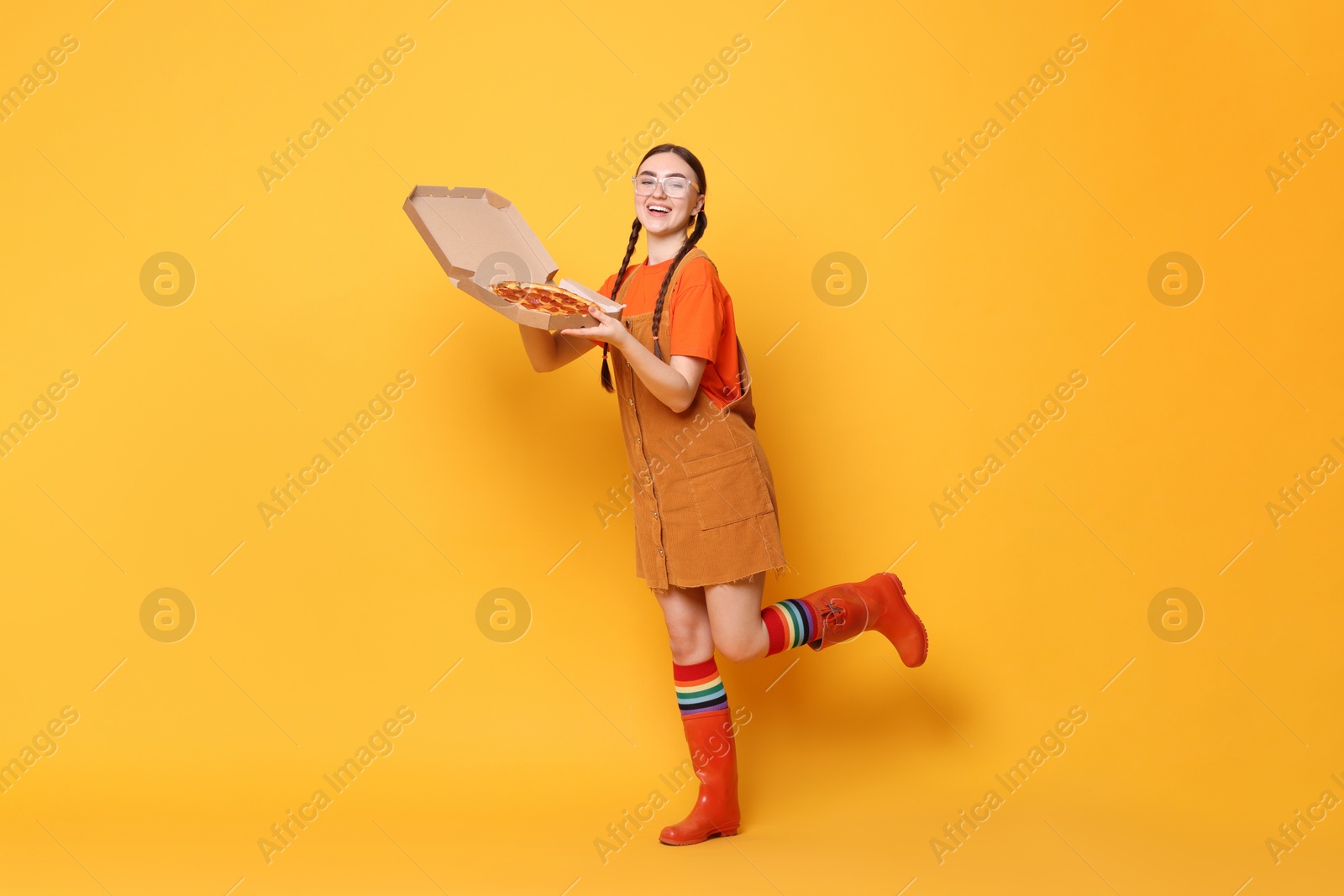 Photo of Beautiful woman with delicious pizza on orange background