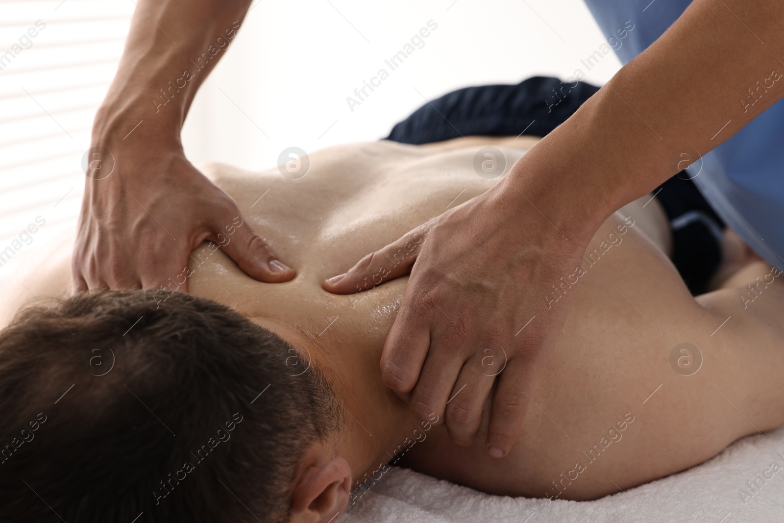 Photo of Professional physiotherapist doing neck massage for his client indoors, closeup