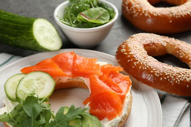 Photo of Delicious bagel with salmon, cream cheese, cucumber and avocado on table, closeup