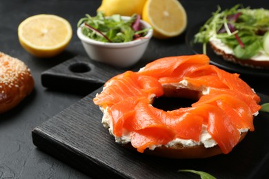 Photo of Delicious bagel with salmon and cream cheese n black table, closeup