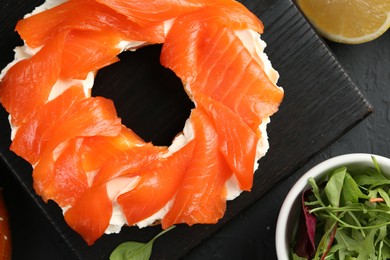 Photo of Delicious bagel with salmon and cream cheese n black table, top view