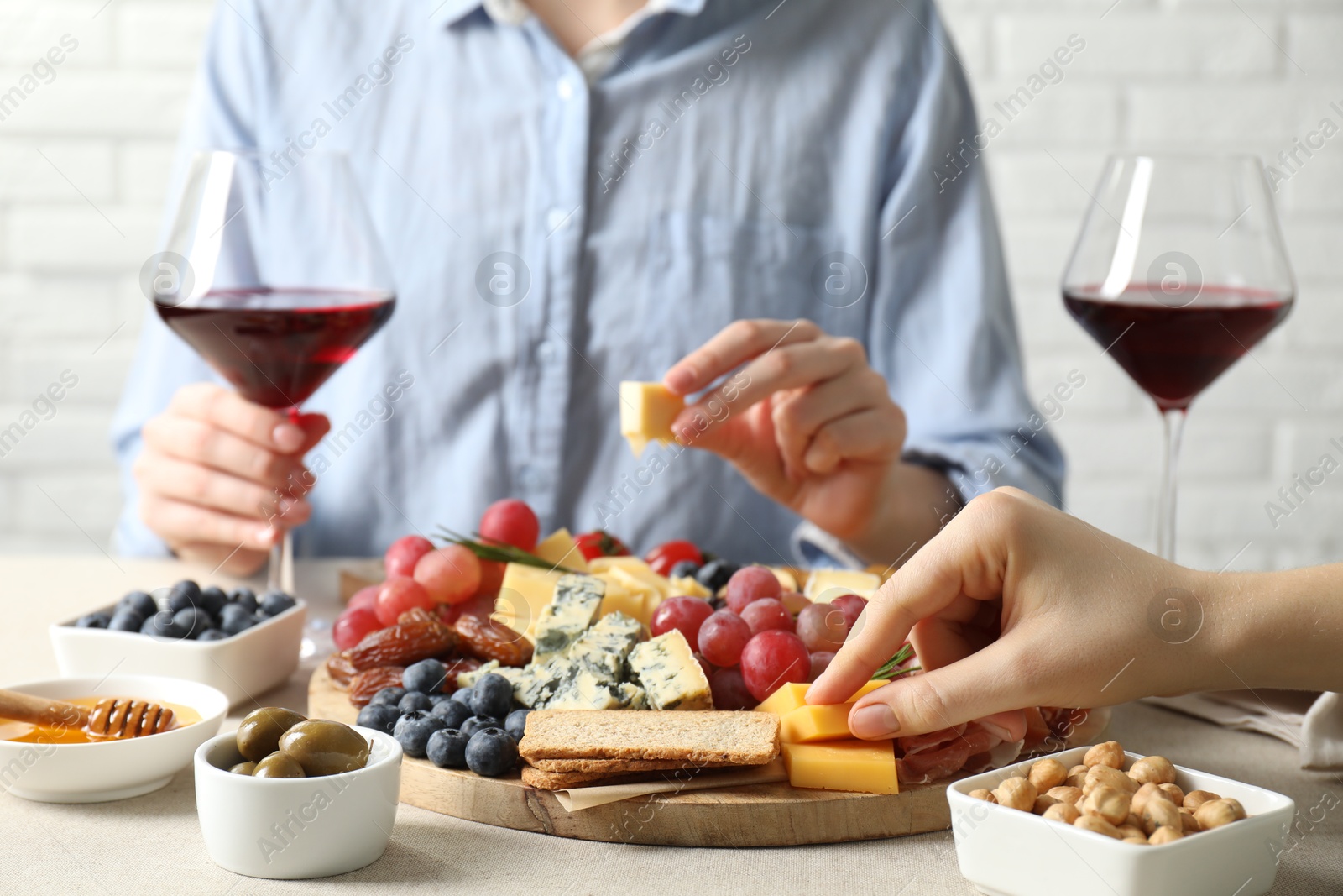 Photo of Women enjoying different snacks and wine during brunch at light grey table indoors, closeup