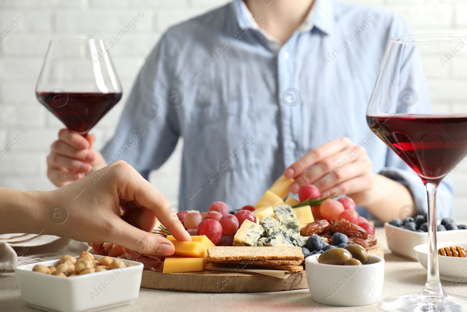 Photo of Women enjoying different snacks and wine during brunch at light grey table indoors, closeup