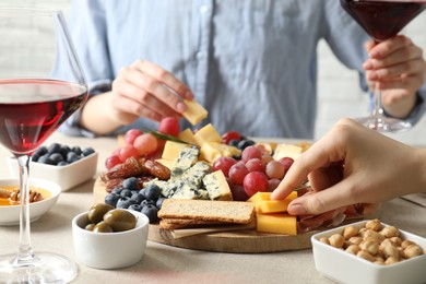 Photo of Women enjoying different snacks and wine during brunch at light grey table indoors, closeup