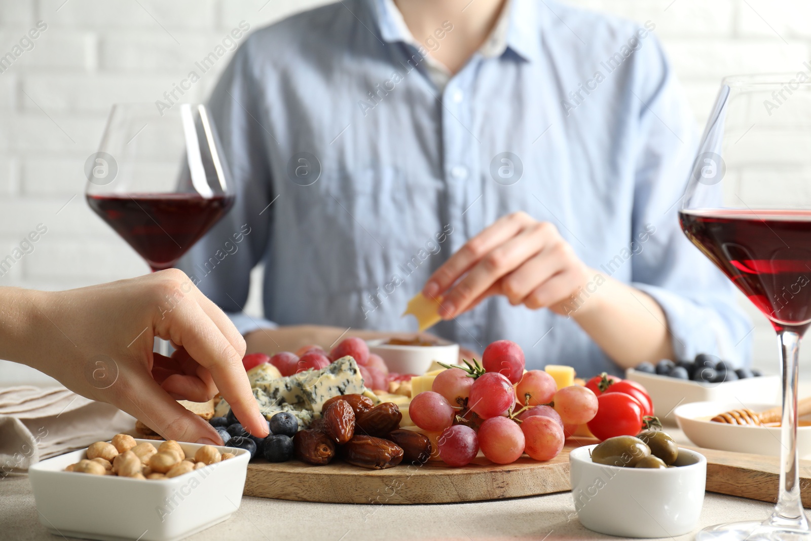 Photo of Women enjoying different snacks and wine during brunch at light grey table indoors, closeup