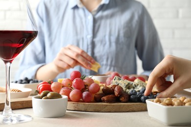 Photo of Women enjoying different snacks and wine during brunch at light grey table indoors, closeup