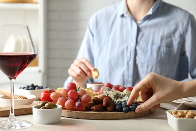 Photo of Women enjoying different snacks and wine during brunch at light grey table indoors, closeup