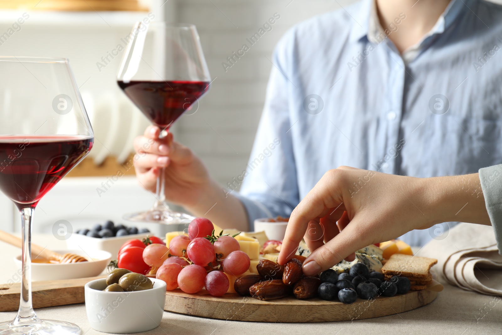 Photo of Women enjoying different snacks and wine during brunch at light grey table indoors, closeup