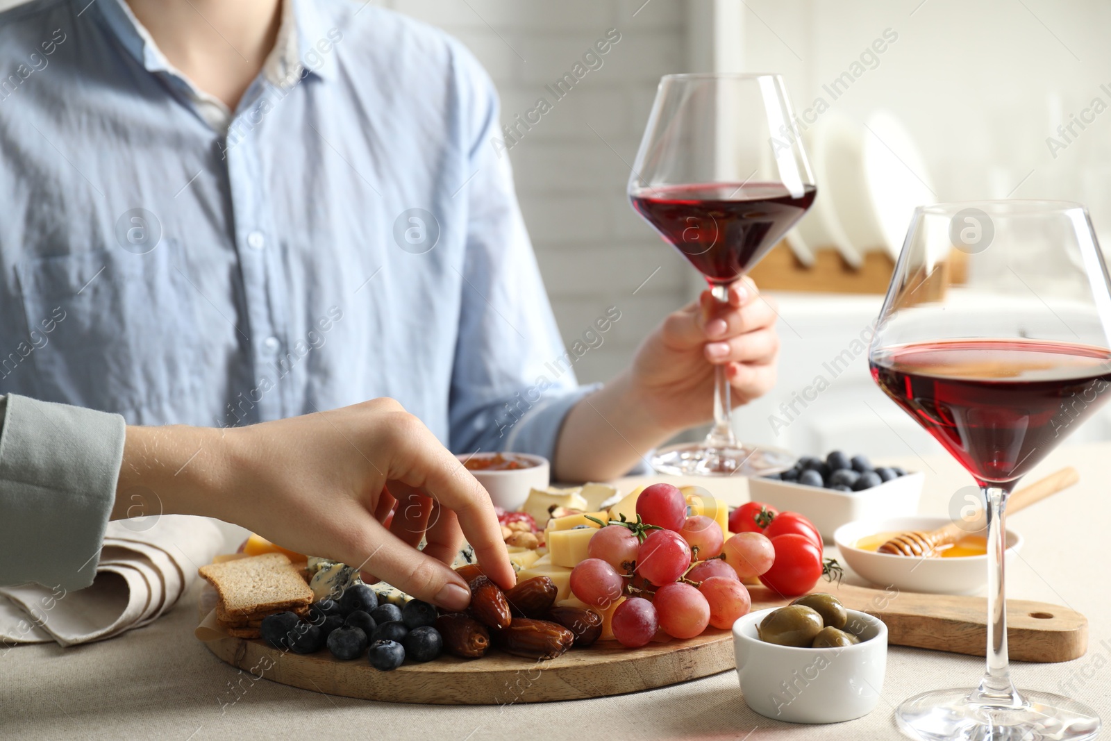 Photo of Women enjoying different snacks and wine during brunch at light grey table indoors, closeup