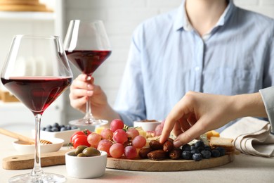 Photo of Women enjoying different snacks and wine during brunch at light grey table indoors, closeup