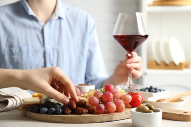 Photo of Women enjoying different snacks and wine during brunch at light grey table indoors, closeup