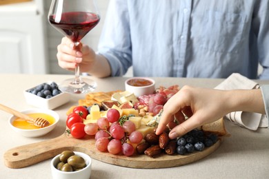 Photo of Women enjoying different snacks and wine during brunch at light grey table indoors, closeup