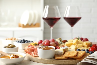 Photo of Different types of delicious cheese, other snacks and wine on light grey table, closeup