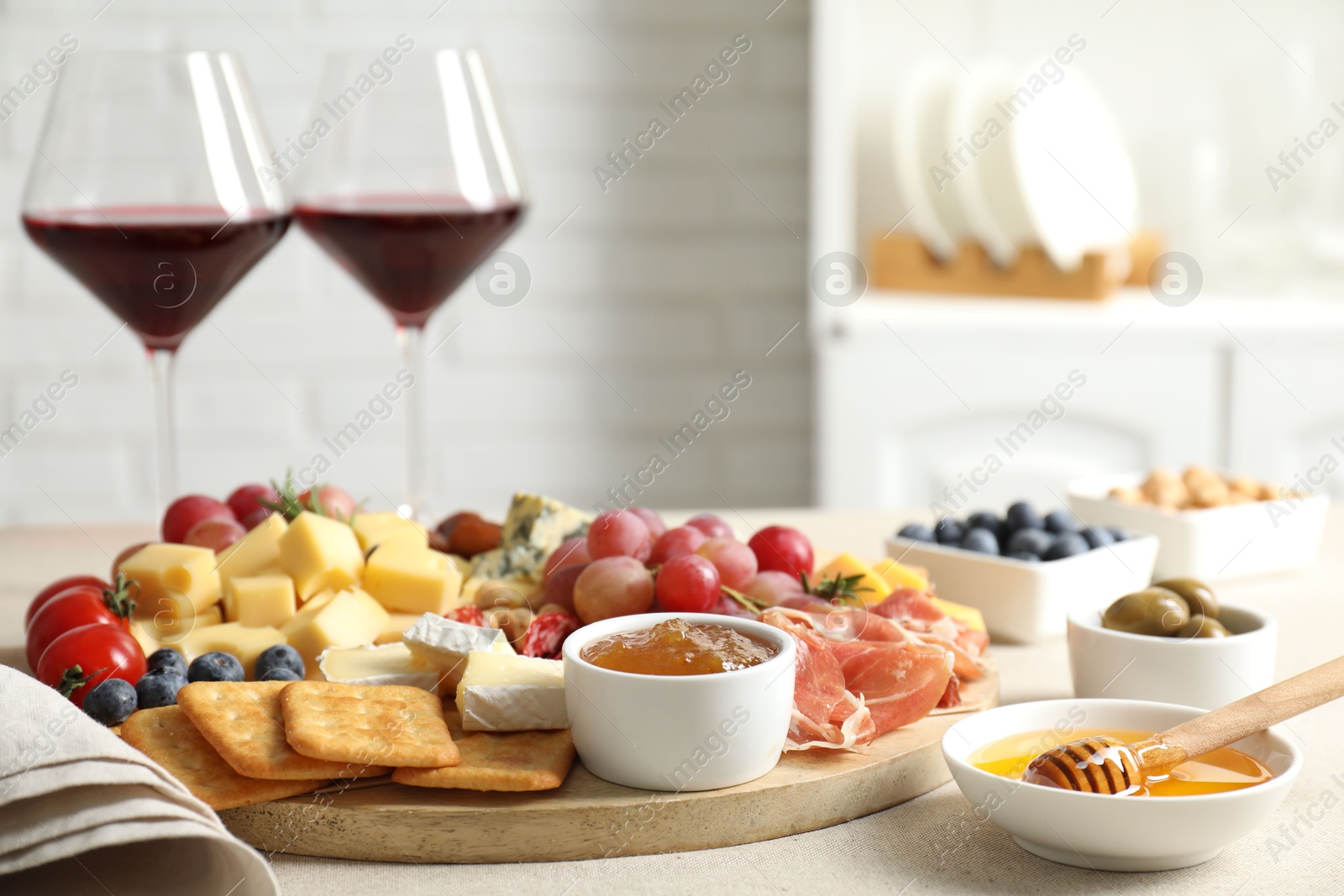 Photo of Different types of delicious cheese, other snacks and wine on light grey table, closeup