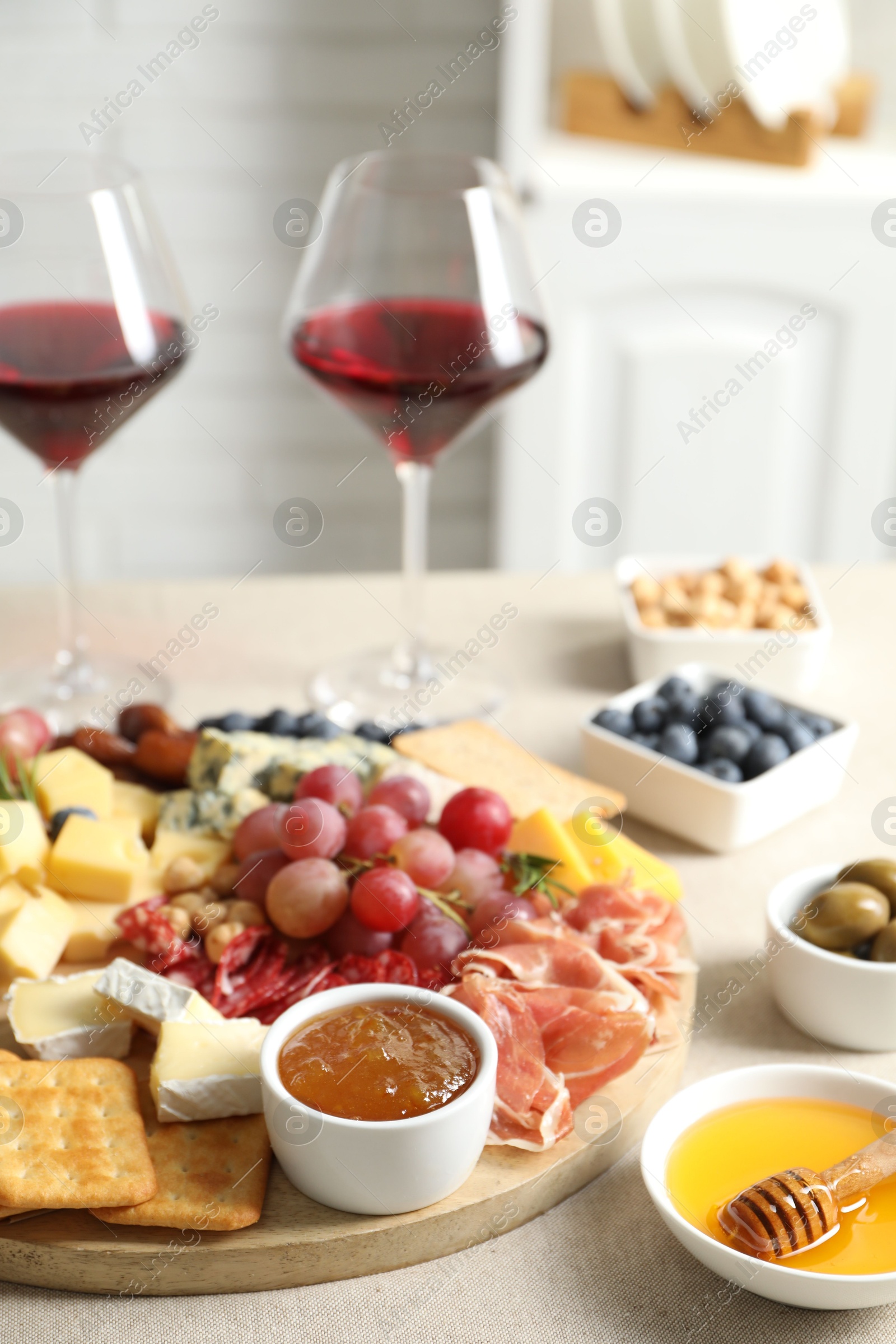 Photo of Different types of delicious cheese, other snacks and wine on light grey table, closeup