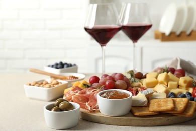 Photo of Different types of delicious cheese, other snacks and wine on light grey table, closeup