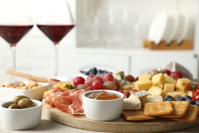 Photo of Different types of delicious cheese, other snacks and wine on light grey table, closeup