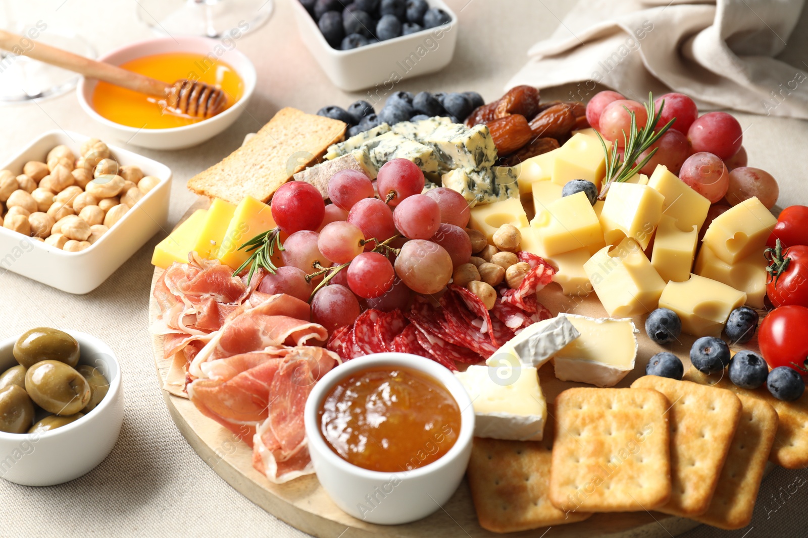 Photo of Different types of delicious cheese and other snacks on light grey table, closeup