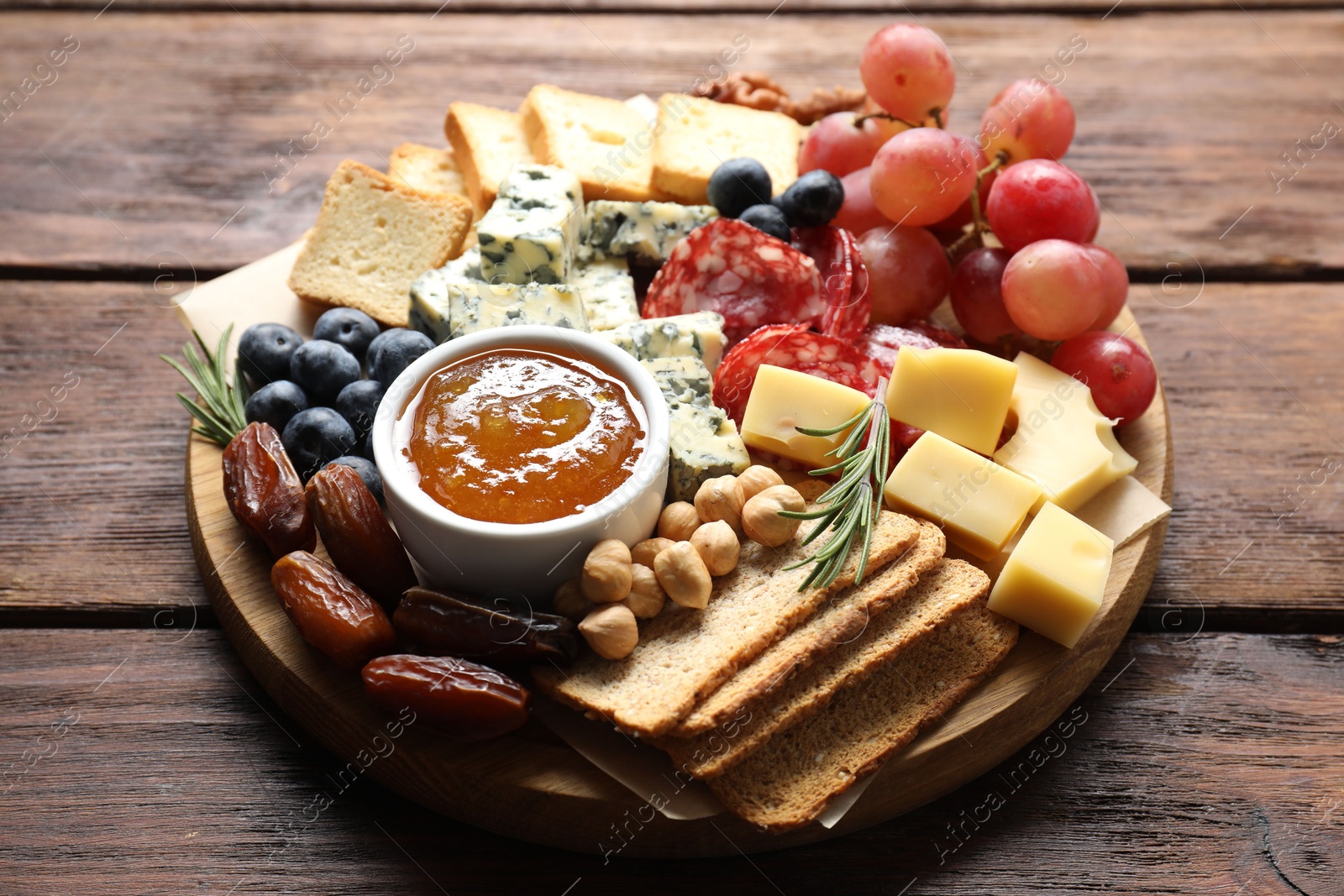 Photo of Different types of delicious cheese and other snacks on wooden table, closeup