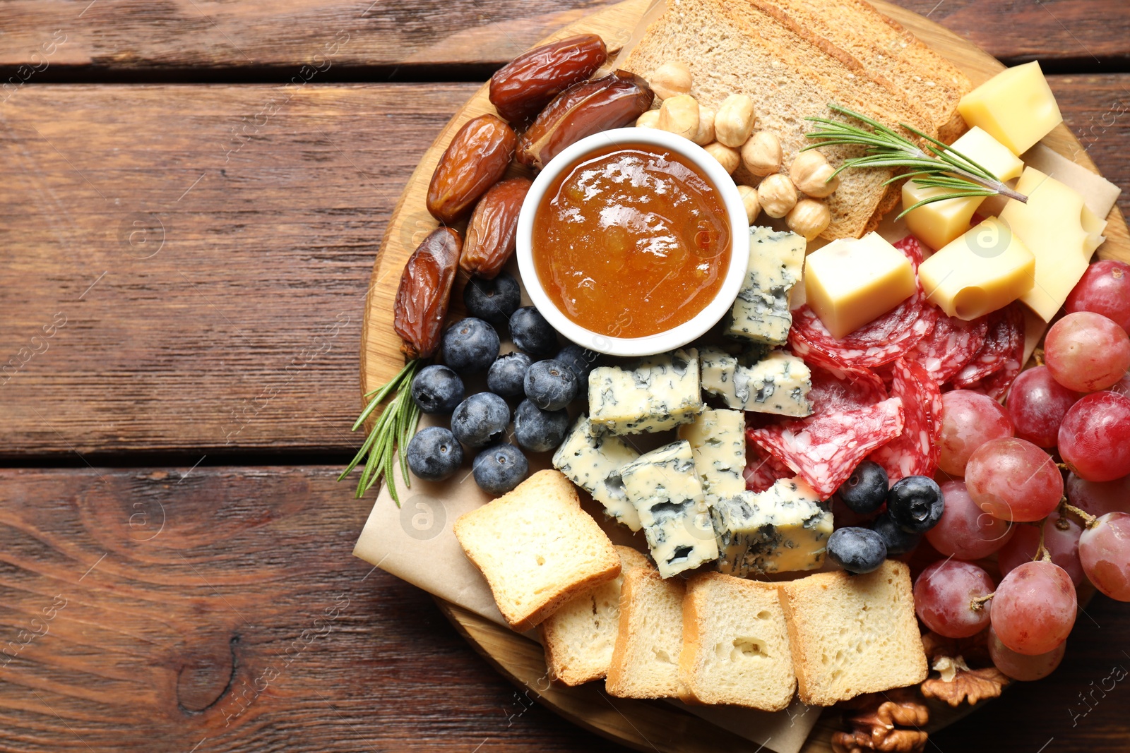 Photo of Different types of delicious cheese and other snacks on wooden table, top view. Space for text