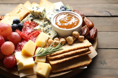 Photo of Different types of delicious cheese and other snacks on wooden table, closeup