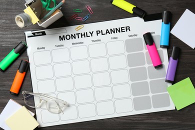 Timetable. Monthly planner and stationery on black wooden table, flat lay