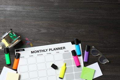 Timetable. Monthly planner and stationery on black wooden table, flat lay. Space for text