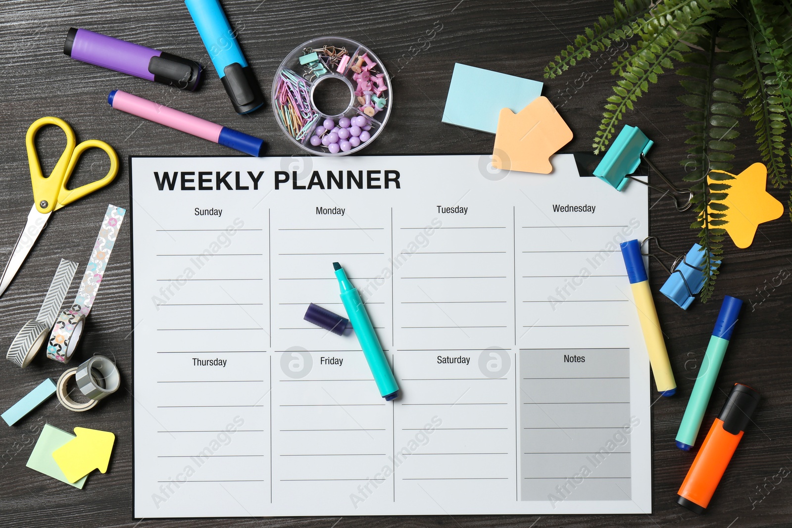 Photo of Timetable. Weekly planner and stationery on black wooden table, flat lay