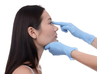 Photo of Doctor checking patient's nose before plastic surgery operation on white background, closeup