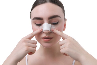 Photo of Woman with medical bandage on her nose after plastic surgery operation against white background