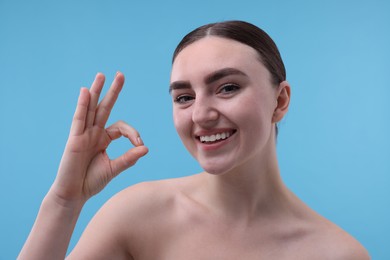 Photo of Beautiful woman showing ok gesture on light blue background