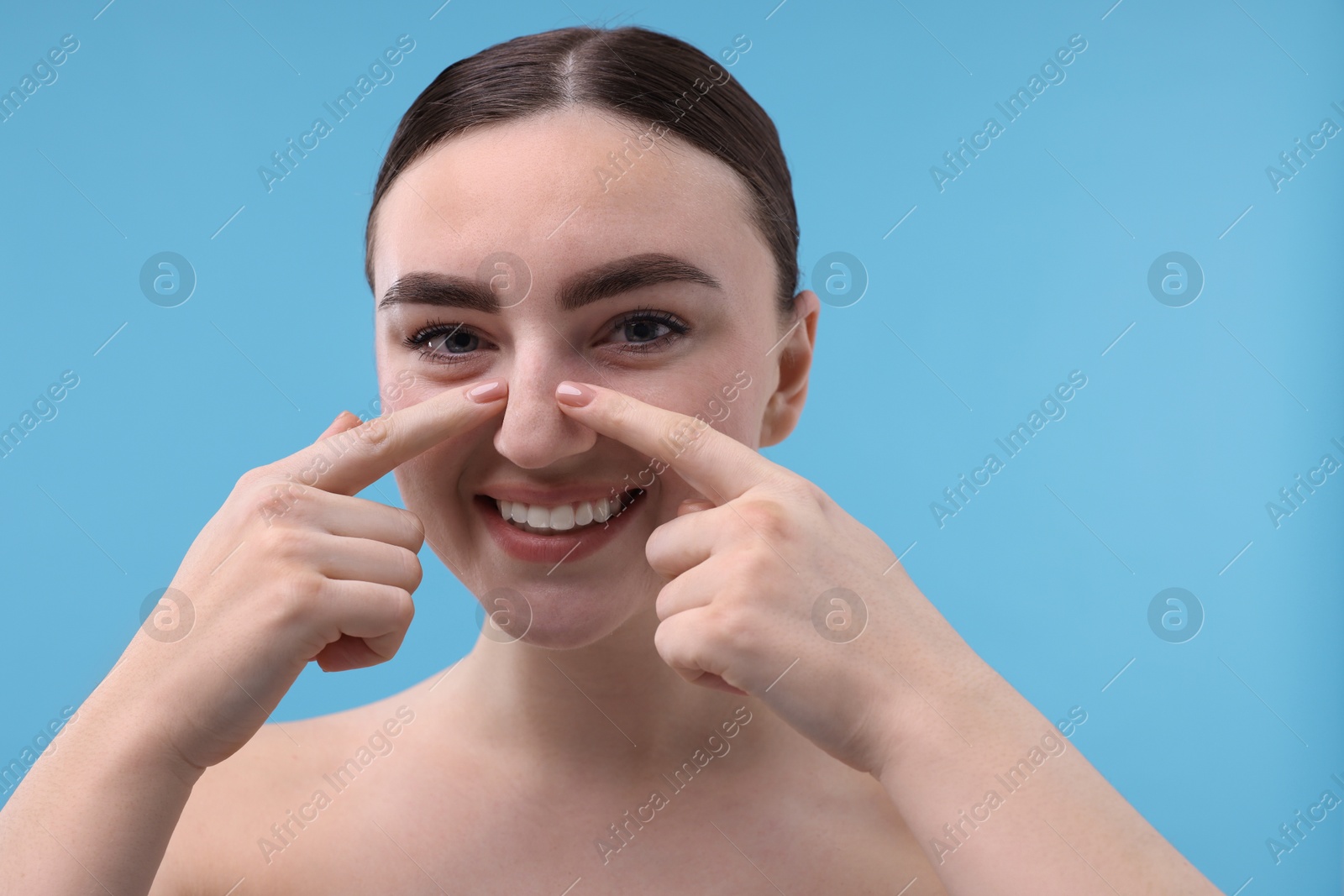 Photo of Woman touching her nose on light blue background