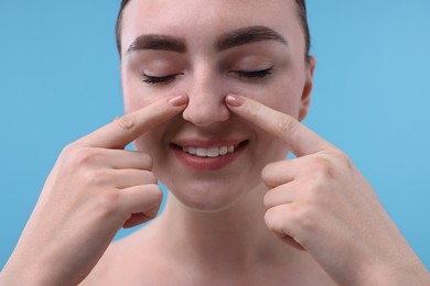 Photo of Woman touching her nose on light blue background