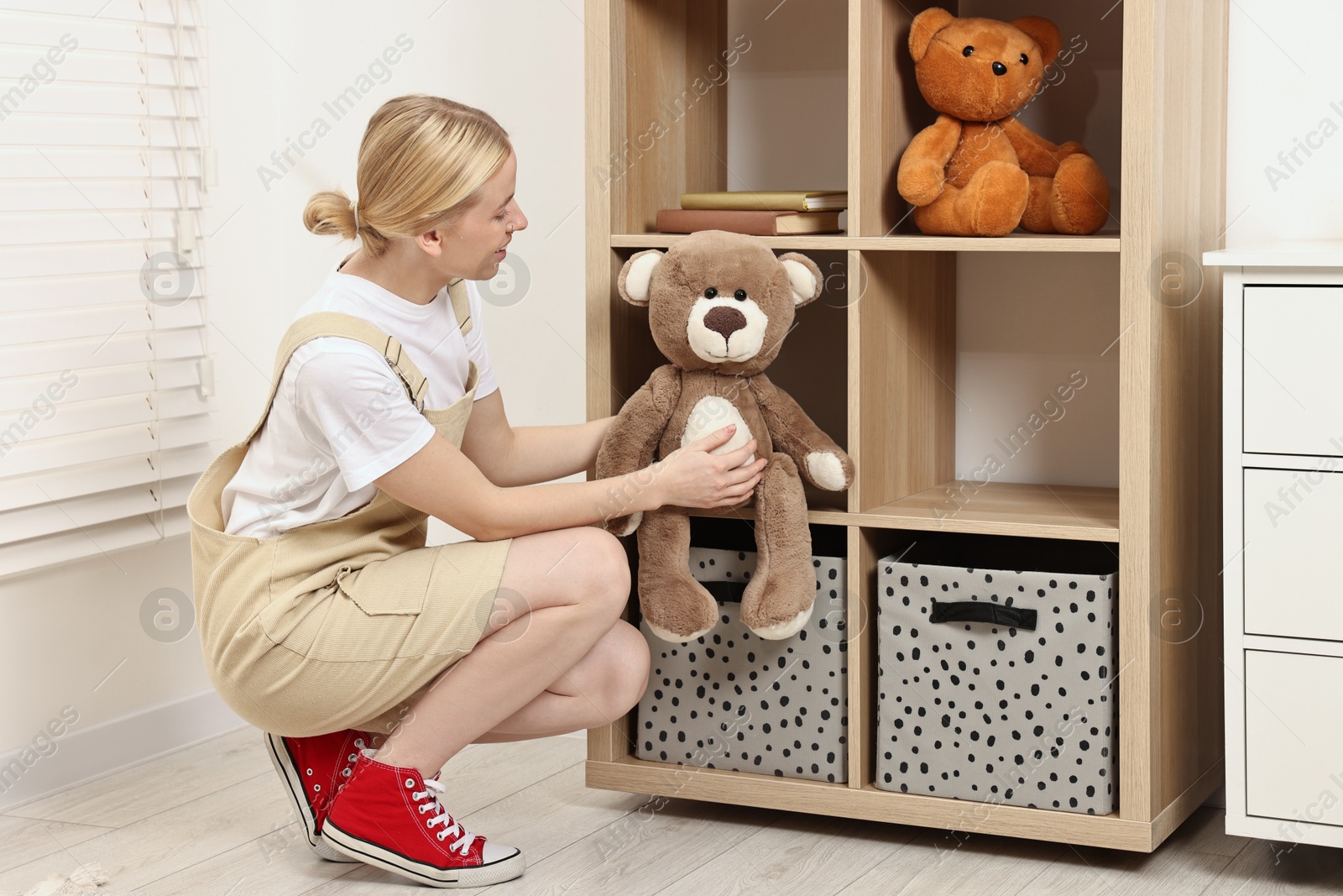 Photo of Female decorator arranging toy onto shelving unit in child's room