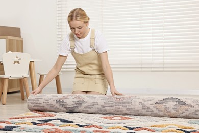 Photo of Female decorator rolling out carpet in child's room