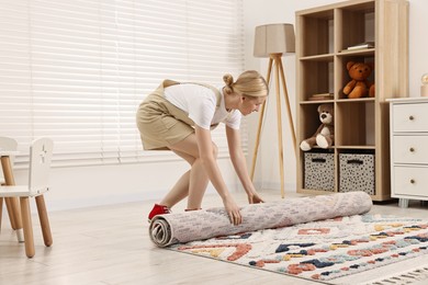 Photo of Female decorator rolling out carpet in child's room