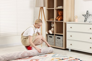 Photo of Happy decorator rolling out carpet in child's room