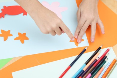 Girl making art project at table indoors, closeup