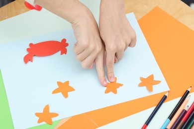 Photo of Girl making art project at table indoors, closeup