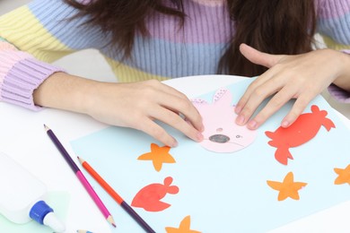 Photo of Girl making art project at table indoors, closeup