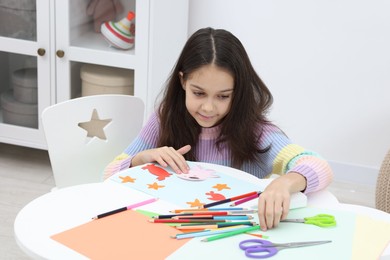 Photo of Girl making art project at table indoors