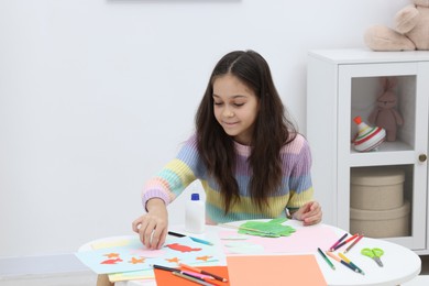 Photo of Girl making art project at table indoors. Space for text