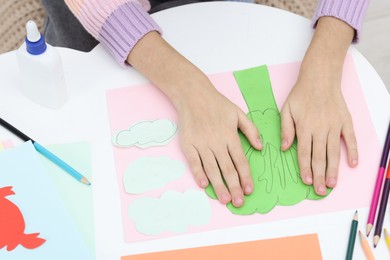 Girl making art project at table indoors, closeup