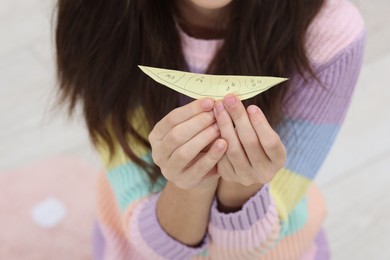 Photo of Girl with cut paper figure for art project at home, closeup