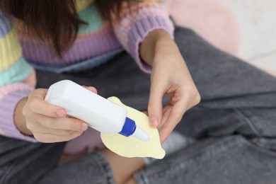 Photo of Girl applying glue onto paper figure for her creative project indoors, closeup. Art and craft