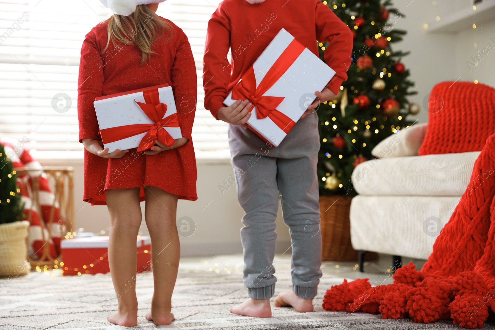 Photo of Little children with Christmas gifts at home, back view